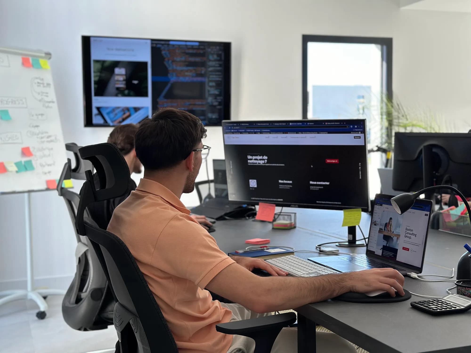 Les bureaux de DYCAST à Perpignan : un développeur travaille sur le site d’un client, code et maquettes sur les écrans
