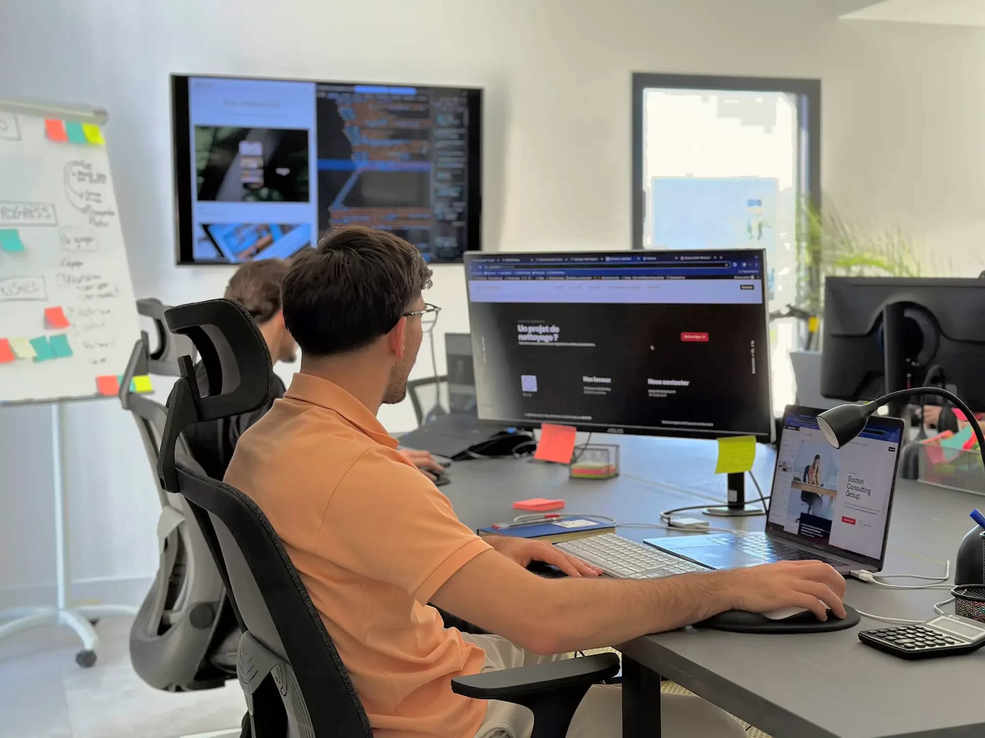 Les bureaux de DYCAST à Perpignan : un développeur travaille sur le site d’un client, code et maquettes sur les écrans