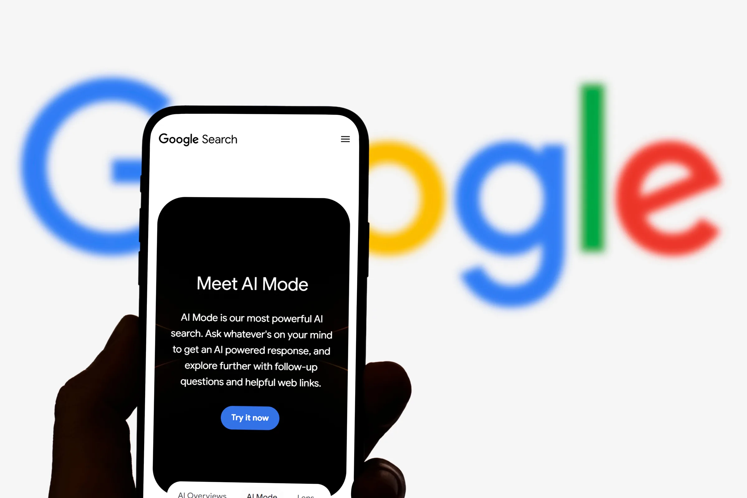 Un smartphone affichant un écran de recherche AI devant un logo flou de Google en arrière-plan