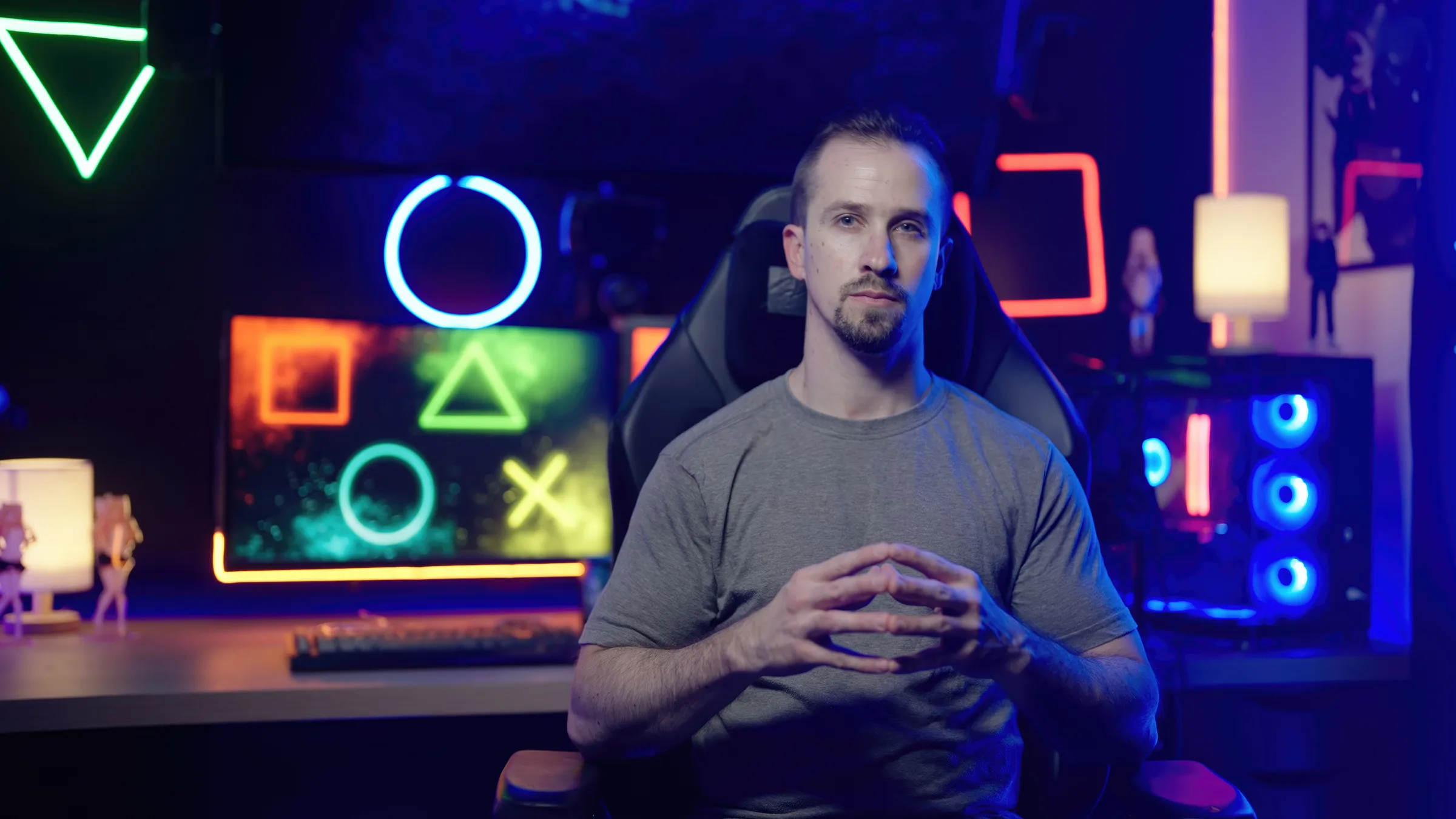 Un homme assis face caméra dans un studio high-tech à éclairages néon colorés, prêt à s'adresser à un public